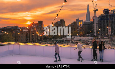 Tabak Dock, London, Großbritannien, 17. November 2019. Skating bei Sonnenuntergang. Die Menschen genießen Sie den spektakulären Blick über die Stadt London in der Londoner trendy Oberlicht Eisbahn, einer Dachterrasse am historischen Tabak Dock Komplex in Wapping, East London. Credit: Imageplotter/Alamy leben Nachrichten Stockfoto