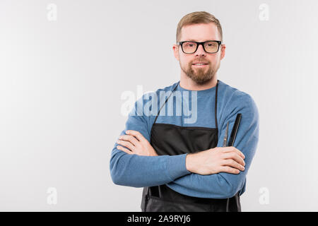 Glückliche junge Bartgeier Friseur in Schürze und Brillen überqueren, um die Arme Brust Stockfoto