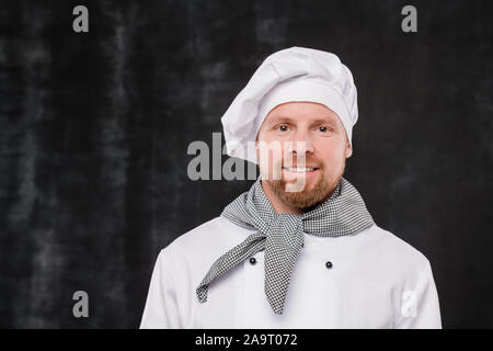 Happy bärtigen Koch in weiße Uniform auf Kamera mit Smile isoliert Stockfoto