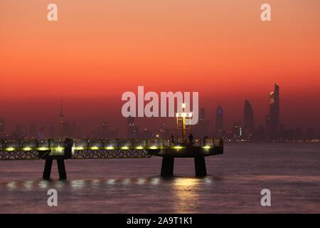 Kuwait City/Kuwait - 10/10/2019: Pier bei Sonnenuntergang mit Skyline Silhouette von Kuwait City im Hintergrund Stockfoto