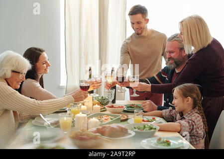 Gerne reifer und jungen Familienmitglieder klirren mit Wein während Weihnachten toast Stockfoto