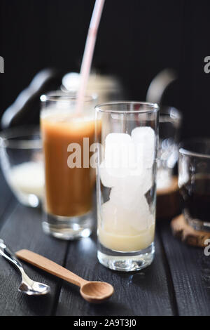 Die eiskaffee. Hohes Glas mit Eiswürfeln und Kondensmilch für das Gießen von Kaffee auf schwarzen Hintergrund selektiven Fokus bereit Stockfoto
