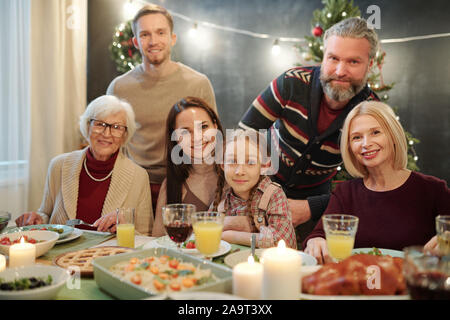 Große familie zu Ihnen schauen, während Sie von serviert Tabelle vor der Kamera sitzen Stockfoto