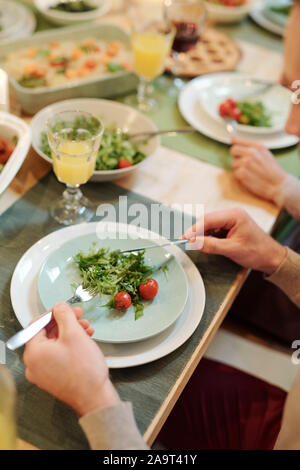 Die Hände der jungen Mann mit Messer und Löffel über Platte mit Bio-lebensmitteln Stockfoto