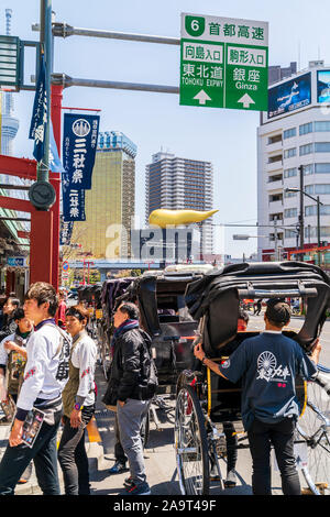 Tokio Asakusa. Reihe von Rikschas und Treiber außerhalb Asakusa Tempel warten auf Passagiere mit Asahi Sitz und die goldene Flamme im Hintergrund. Stockfoto