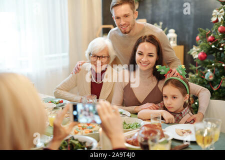 Freundliche liebevolle Familie sucht auf Smartphone Kamera von festlichen Abendessen Stockfoto