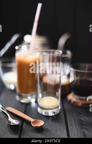 Eis Kaffee mit Kondensmilch in hohe Gläser auf schwarzem Hintergrund ausgewählte konzentrieren Stockfoto