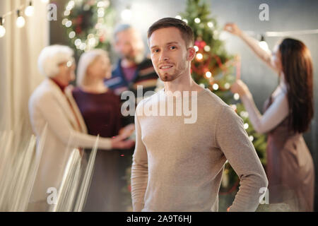 Glückliche junge Mann in beige Pullover stand vor der Kamera Stockfoto