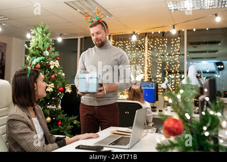 Junge Unternehmer mit xmas Kopfband, die gegenwärtig zu einer der Kollegen Stockfoto