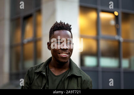 Portrait von lächelnden african-american man in stilvolle Jacke auf Stadt Straße in den Abend. Stockfoto
