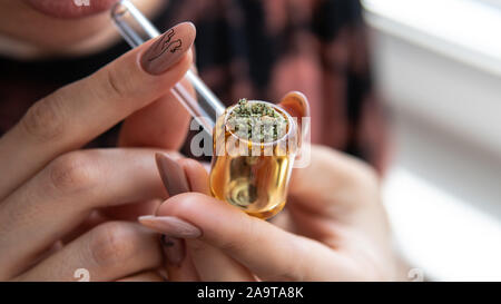 Europäische Mädchen Marihuana raucht, durch ein Glasrohr. Rauchen von Cannabis durch das Glas Rohr Stockfoto