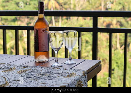 10.14.2019 Ubud, Bali, Indonesien, eine Flasche rose Wein und zwei Gläser auf dem Balkon mit Blick auf die Reisterrassen, romantischen Abend für zwei Stockfoto