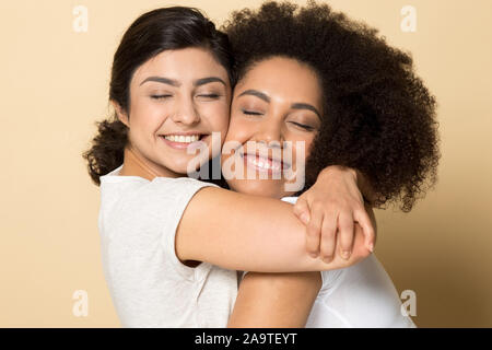 Lächelnd diverse Mädchen mit geschlossenen Augen, besten Freunde umarmen Stockfoto