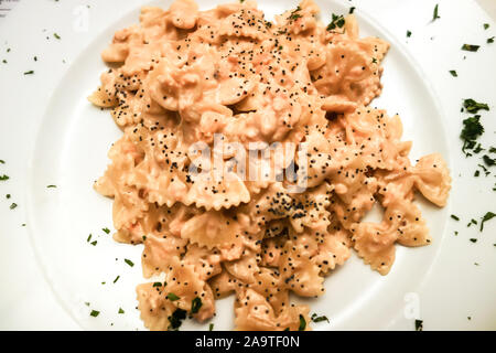 PALMERO, Italien - 18.Oktober.2019: Schmetterling Pasta, auch als farfalette mit Lachs gewürzt mit Pfeffer schwarz bei Pizza e Cucina serviert werden. Stockfoto