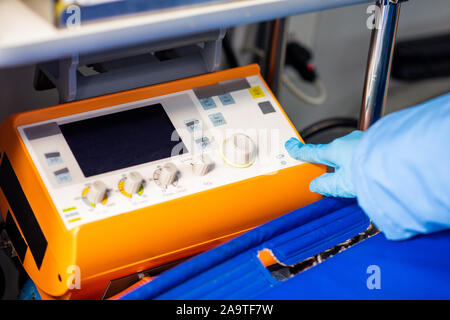 Sanitäter in Handschuhe Druck auf den Knopf an der medizinische Erste Hilfe Ausrüstung beginnen. Es Stockfoto