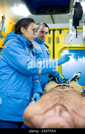 Zwei junge Sanitäter Vorbereitung dropper für kranke Mann innerhalb der Ambulanz Auto Stockfoto