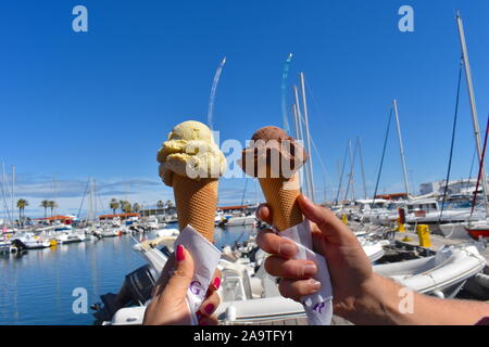 Männliche und weibliche Hände halten Eis an der Promenade im Süden von Frankreich. Pistazien und mit Schokoladegeschmack Eis in der Waffel Kegel. Eis. Stockfoto
