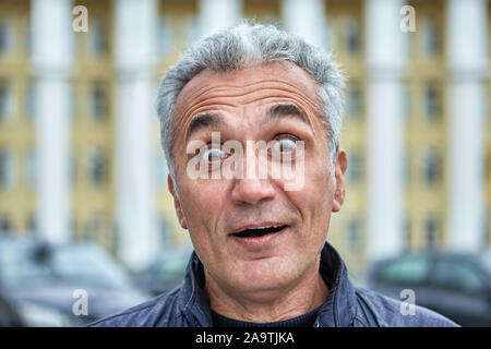 Closeup Portrait von einem überraschten Mann mit kurzen grauen Haaren und über 50 Jahre. Im mittleren Alter Mann mit Pop-eyed im Freien. Entsetzen in den Augen o Stockfoto