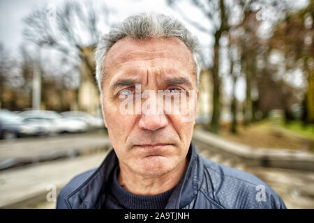 Ein grauhaariger Mann mit einem kurzen Haarschnitt über 50 Jahre alt, sorgfältig sieht vor ihm draußen, er sieht aus wie ein Mitarbeiter von Strafverfolgungsbehörden agenc Stockfoto