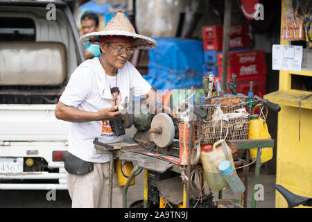 Ein Filipino Mann mit einem Schleifstein ein Messer, Nachschärfen, Cebu City, Philippinen Stockfoto