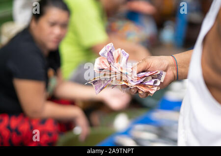 Ein Mann hält eine Reihe von Peso Banknoten, die auf einem Markt in Cebu City, Philippinen Stockfoto