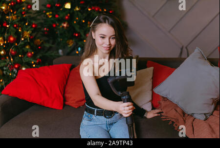 Junge Frau blogger ist die Ausstrahlung am Telefon mit einem Stabilisator. Weihnachten und neues Jahr. Seite hustle. Innen- Stockfoto