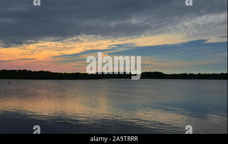 Blick über den großen See (in der Norfolk Broads, UK) bei Sonnenuntergang. Blaues Wasser und Himmel drehen orange, rot und rosa inmitten der Wolken, in der ge wider Stockfoto