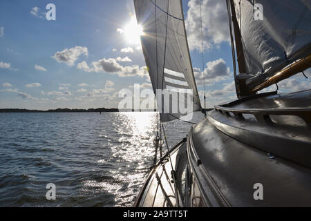 Kabine und Ausleger auf einem traditionellen hölzernen Segelyacht, segeln in Richtung der Sonne auf ein breiter See in der Norfolk Broads (UK). Sonnenlicht auf der Stockfoto