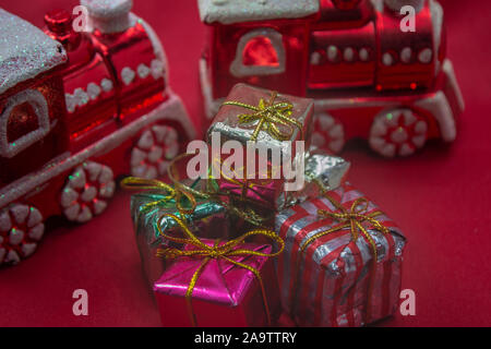 Rote Zugornamente mit Weihnachtsgeschenken auf rotem Hintergrund, Foto-Illustration Stockfoto