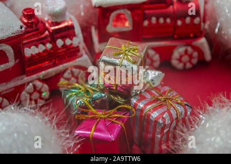 Rote Zugornamente mit Weihnachtsgeschenken auf rotem Hintergrund, Foto-Illustration Stockfoto