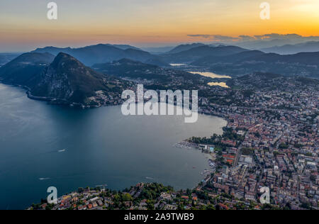 Antenne drone schoß vor Sonnenuntergang der Schweizer Stadt Lugano und Monte Salvatore von Lago di Lugano anzeigen Stockfoto