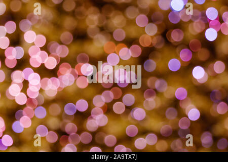 Beleuchtete Abstrakte runde rosa, violett, magenta, blau und gold Bokeh auf goldenem Hintergrund. Bunte Glitzer bokeh Aus Lupenansicht für Glühlampen. Stockfoto