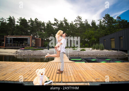 Liebevolle Junge paar Küsse auf einen Holzsteg. Liebesfilm auf der Pier. Stockfoto