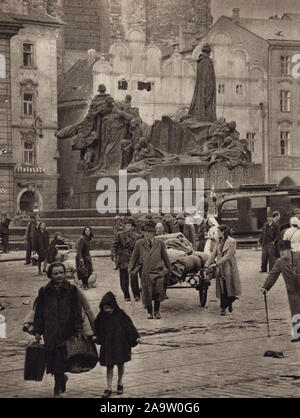 Deutsche Flüchtlinge mit ihren Habseligkeiten vor dem Denkmal von Jan Hus auf dem Altstädter Ring in Prag, Tschechoslowakei, im Mai 1945. Schwarz-weiß Foto von tschechischen Fotografen Stanislav Hulík in der Tschechoslowakischen Buch 'Memory Buch des Prager Aufstands" veröffentlicht (památník Pražského povstání") im Jahr 1946 herausgegeben. Das Foto war wahrscheinlich am Nachmittag des 8. Mai 1945, als die deutsche Bevölkerung von Prag war in der Lage die Stadt nach der Kapitulation der Deutschen Garnison nach dem Prager Aufstand zu verlassen. Das Haus Zur Steinernen Glocke (Dům u Kamenného zvonu) vor der Wiederherstellung der Stockfoto