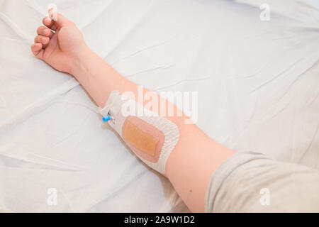 Hand eines Patienten mit einer Infusion Katheter auf weißem Gewebe in armen Krankenhaus Stockfoto