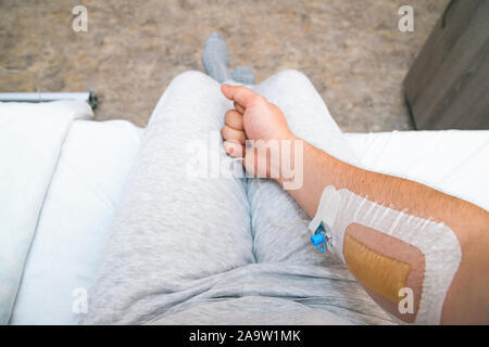 Die Hand des Patienten mit Faust mit Infusion Katheter. Erste Person anzeigen Stockfoto