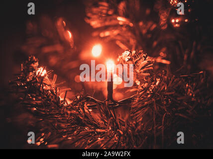 Red christmas Licht auf einen Weihnachtsbaum. Die Zweige Leuchten. Verschwommenen Hintergrund. Stockfoto