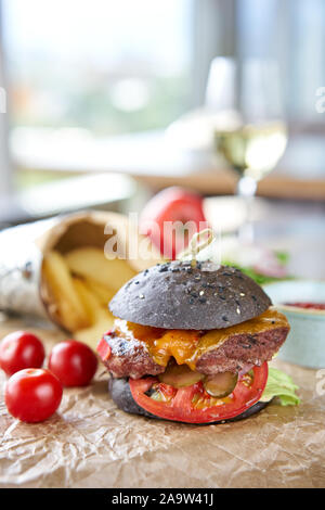 Cheeseburger mit Salat, Tomaten, Pommes frites und geschmolzenem Käse. Der Tisch im Restaurant. Ungesunde Lebensmittel. Stockfoto