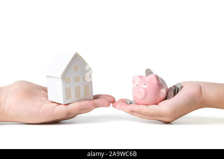 Hände halten rosa Sparschwein und Papier Modell Haus auf weißem Hintergrund, Geld sparen für neue Haus Konzept kaufen Stockfoto