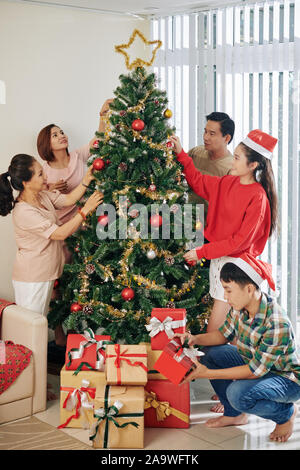 Große glückliche vietnamesische Familie genießen Weihnachtsbaum gemeinsam schmücken Stockfoto