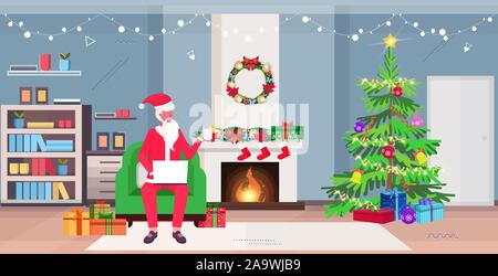 Weihnachtsmann im Sessel sitzt mit Laptop und Tee trinken, modernes Wohnzimmer mit Kamin Tannenbaum und Geschenkboxen frohe Weihnachten Neujahr feier Konzept horizontale voller Länge Vektor illustration Stock Vektor
