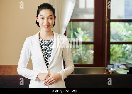 Positive jungen hübschen Spa Salon an der Rezeption stehen am Arbeitsplatz und lächelnd an Kamera Stockfoto