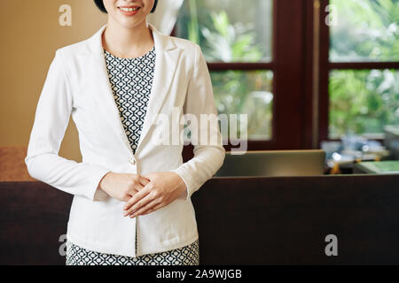 Zugeschnittenes Bild von lächelnden Dame in gepflegter Kleidung, die Sie Grußansage in Spa Salon oder Boutique Hotel Stockfoto