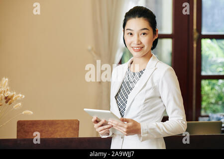 Junge schöne Spa Salon an der Rezeption stehen am Arbeitsplatz mit Tablet-PC in der Hand Stockfoto