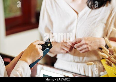 Weibliche Client zu warten, wenn der Rezeptionist Durchziehen der Kreditkarte und die Annahme, selektiver Fokus Stockfoto