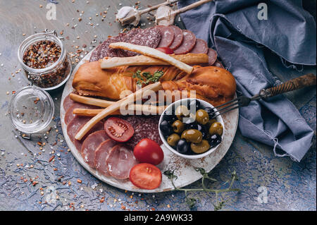 Mediterrane Speisen. Ansicht von oben sortiert aus Fleisch und Käse auf einem runden Schneidebrett. Roh geräucherter Wurst, Schinken, Käse, Oliven. Platz kopieren Stockfoto