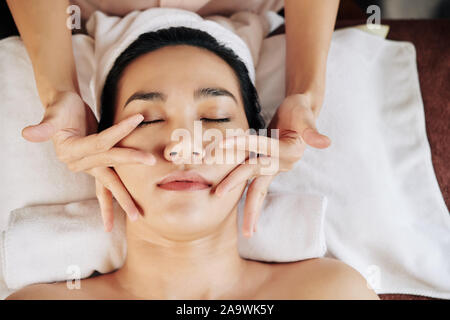 Junge asiatische Frau liegend auf Massage Tisch und genießen Gesichtsmassage in Schönheitsklinik, Ansicht von oben Stockfoto