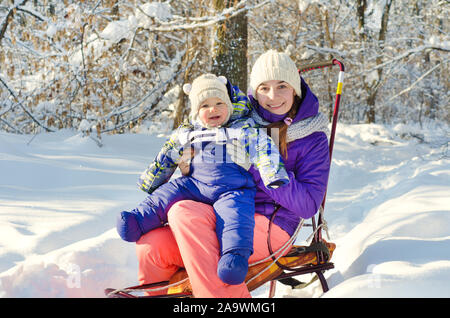 Mutter und Kind auf dem Schlitten sitzen Stockfoto