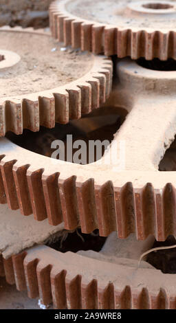 Riesige Eisen getrieben. Stapel von großen und alten industriellen Zahnräder in den Staub Stockfoto