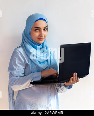 Geschäftsfrau im Hijab in einem Video-chat auf dem Laptop. Cute muslimische Frau in der traditionellen islamischen Kleidung - hijab Holding in die Hände schwarzer Laptop Stockfoto